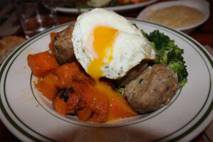 Gluten Free Chicken meatballs with an egg on sautéed vegetables at The Meatball Shop