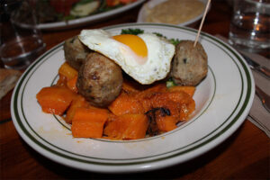 Gluten Free Chicken meatballs with an egg on sautéed vegetables at The Meatball Shop