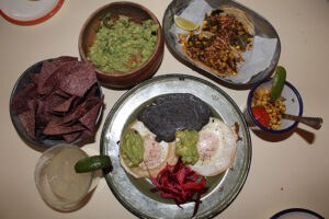 Guacamole and blue corn tortilla chips, sunny side up egg tacos, esquites, veggie tacos at Tijuana Picnic