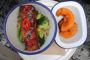 The man bowl with w/ teriyaki salmon, steamed broccoli, pickled chili, sesame seeds and butternut squash side at The Good Life Eatery